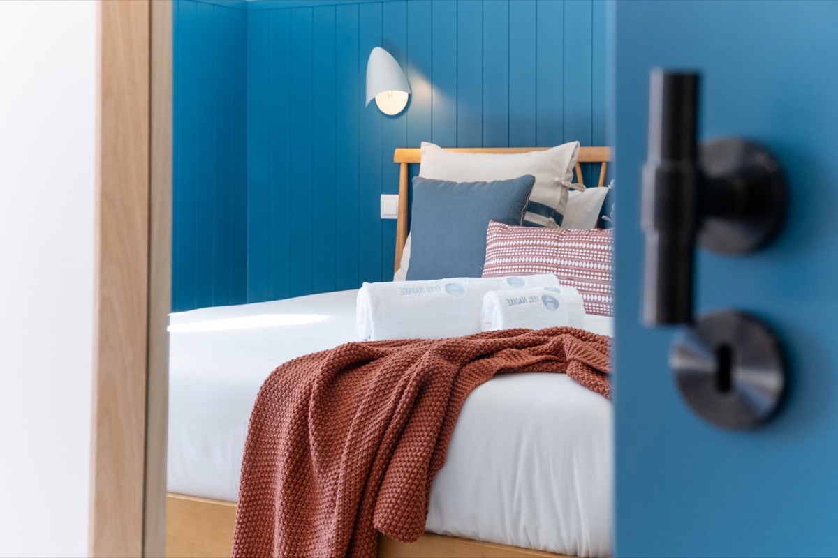 Quarto com a cama feita e as toalhas da Feel Nazaré